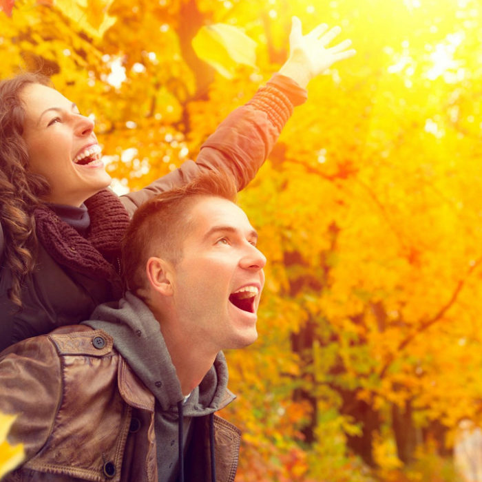 Fröhliches Paar vor Bäumen in herbstlicher Färbung